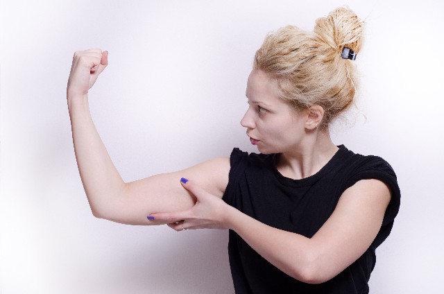 二の腕の感触を確かめる女性